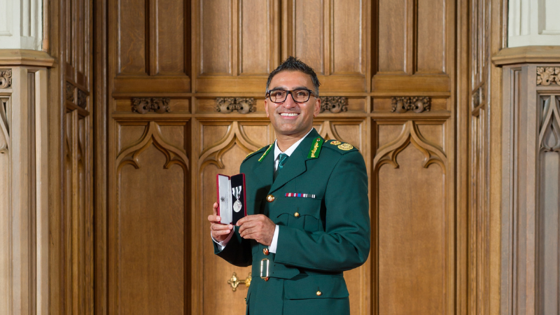 Salman wearing in green ambulance dress suit holding medal.