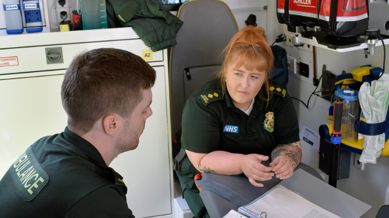 Senior Paramedic and Paramedic (Left) sat down talking in the back of and ambulance