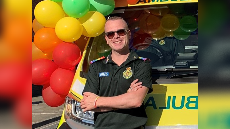 Adam stood infront of an ambulance that has balloons on it