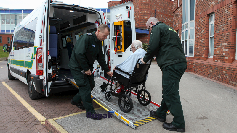 Patient transport service ambulance crew pushing a patient onto the back of an ambulance.