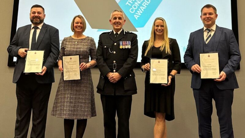 A group of people standing on a stage smiling with their certificates